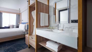 A hotel room with a bed, a bathroom with a sink, and a large mirror.