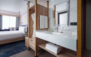 A hotel room with a bed, a bathroom with a sink, and a large mirror. - Hilton Garden Inn Samarkand (Samarkand)
