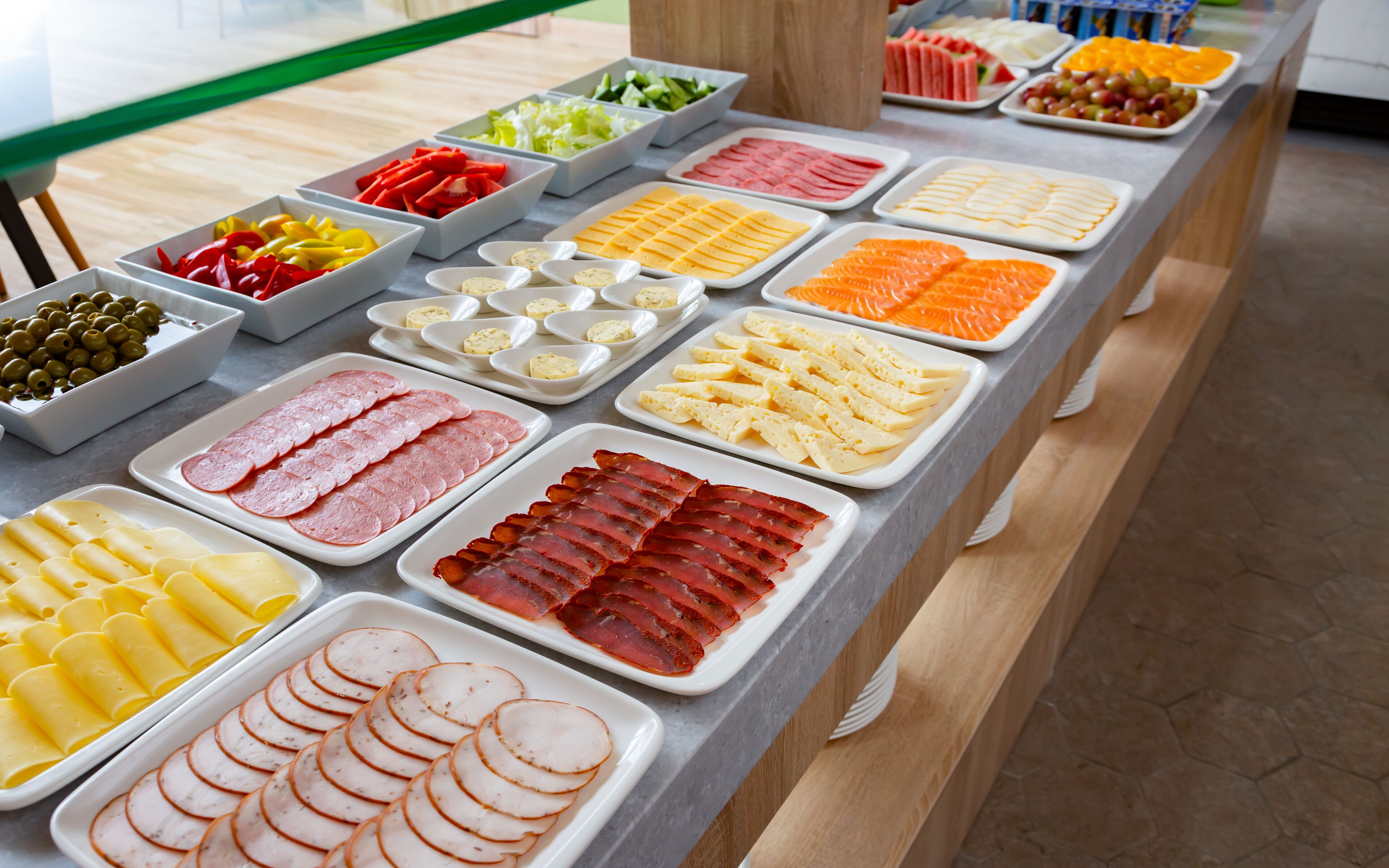 A buffet with various food items including meats, cheeses, and fruits.