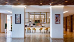 A modern bar area with a wooden ceiling, a bar counter, and three yellow chairs. - Hilton Garden Inn Samarkand (Samarkand)