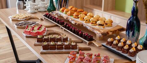 Una mesa de buffet con diferentes opciones de comida, incluyendo pasteles, sándwiches y postres.