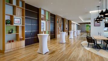 A modern interior with wooden floors, white tables, and a green accent wall.