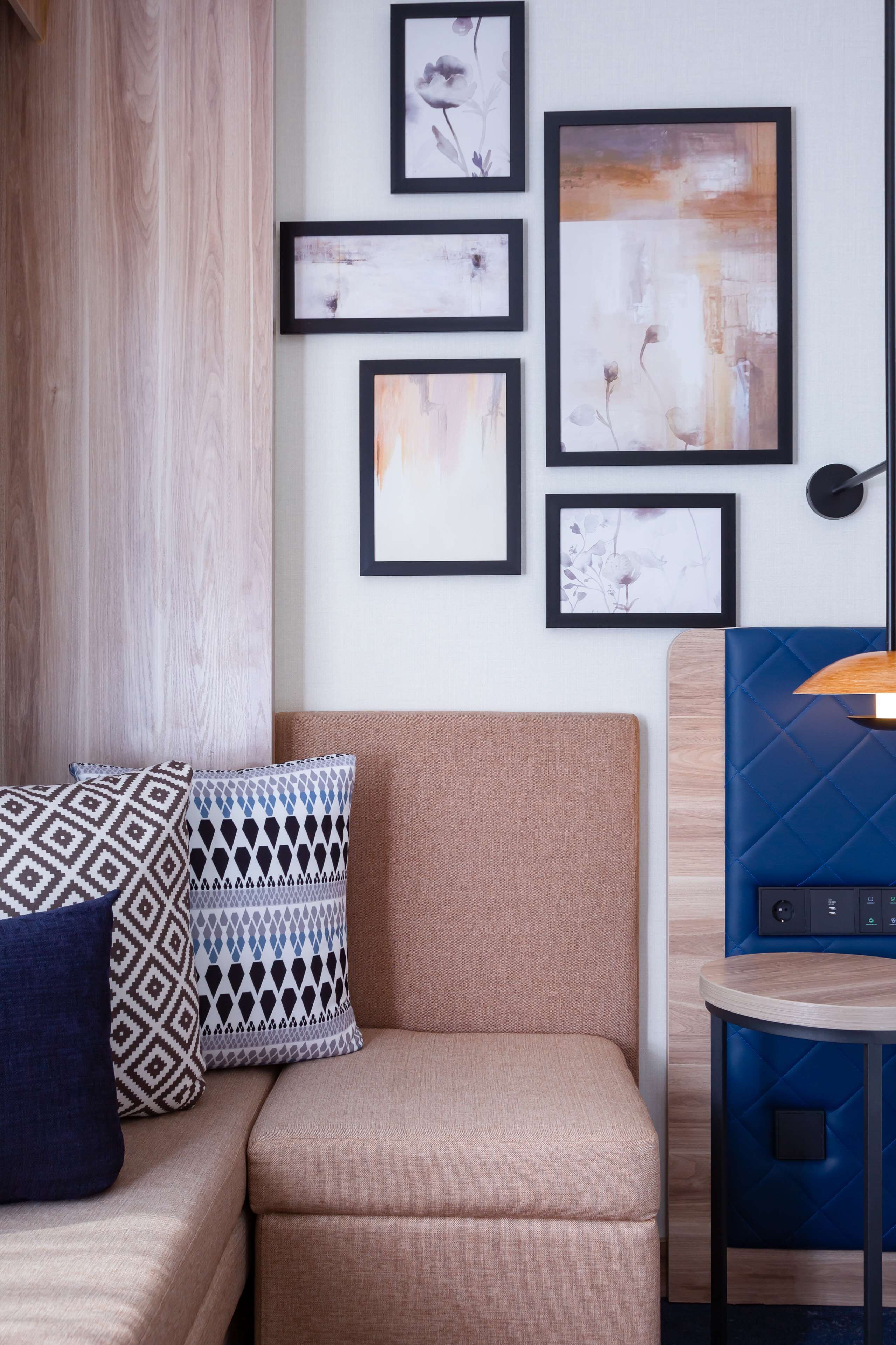Un salon moderne avec un canapé beige, des coussins à motifs et un mur d’accent bleu.