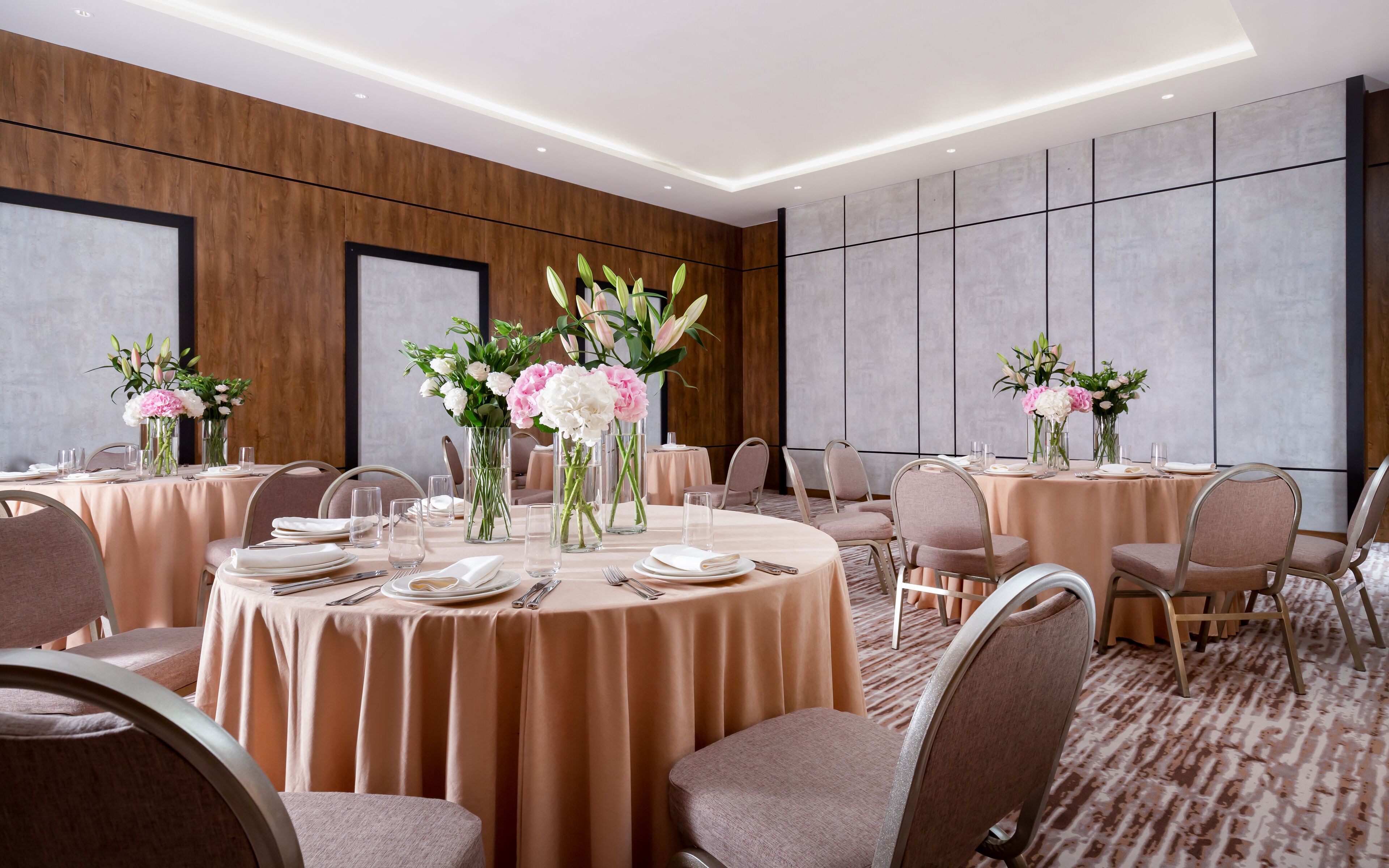 A conference room with round tables, chairs, and floral centerpieces.