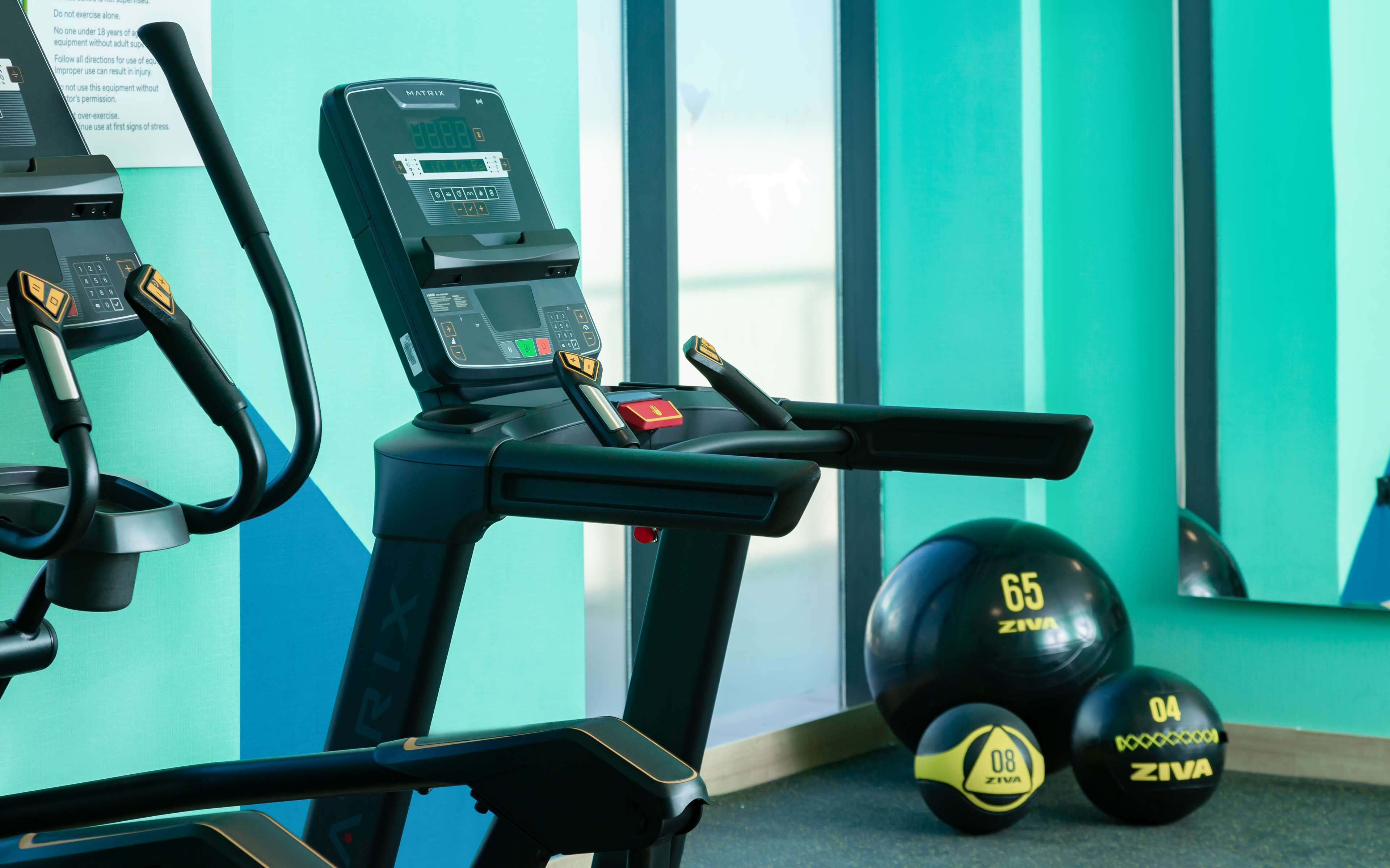 Un gimnasio con equipo de ejercicio, incluyendo una cinta de correr y pesas.