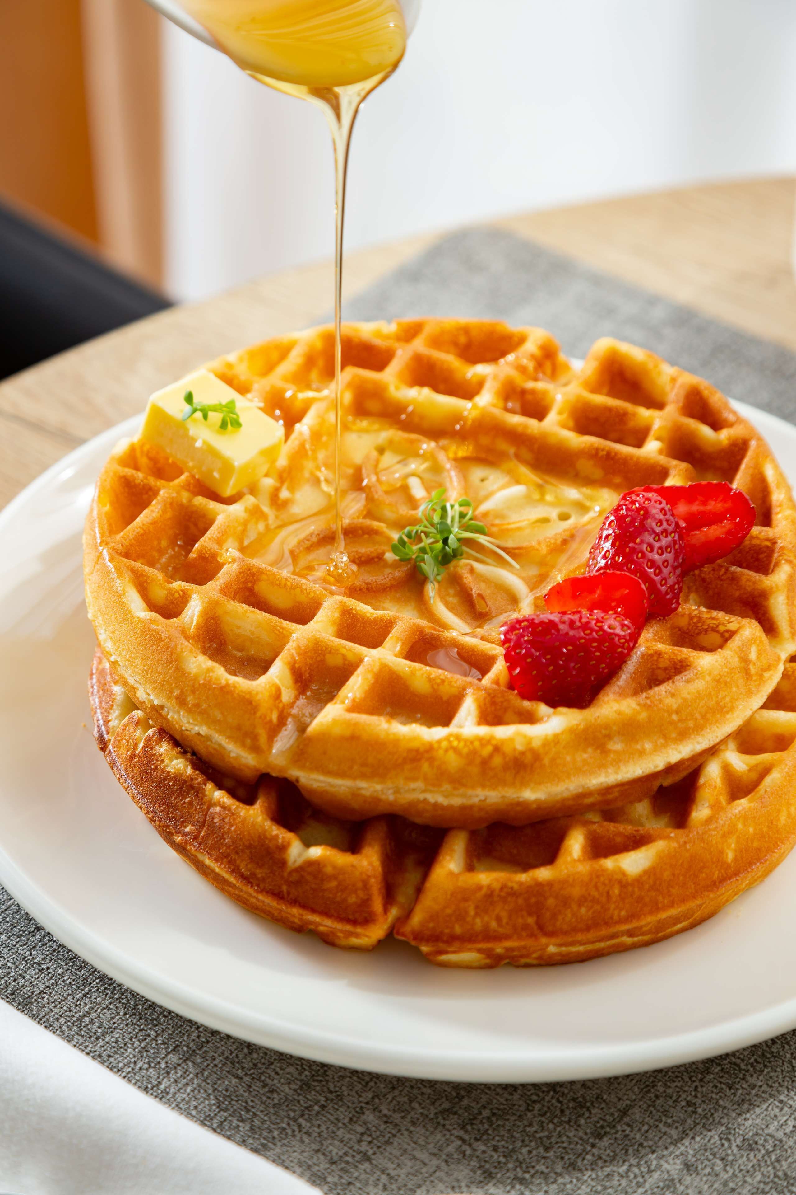 A waffle with syrup and strawberries on a plate.