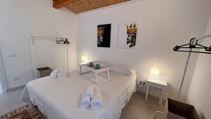 A bedroom with a large bed, two bedside tables with lamps, a wooden ceiling, and two wall-mounted artworks. - Villa Samadoel (Santa Maria del Focallo)