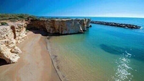 A coastal beach with a rocky cliff and calm waters. - Villa Samadoel (Santa Maria del Focallo)
