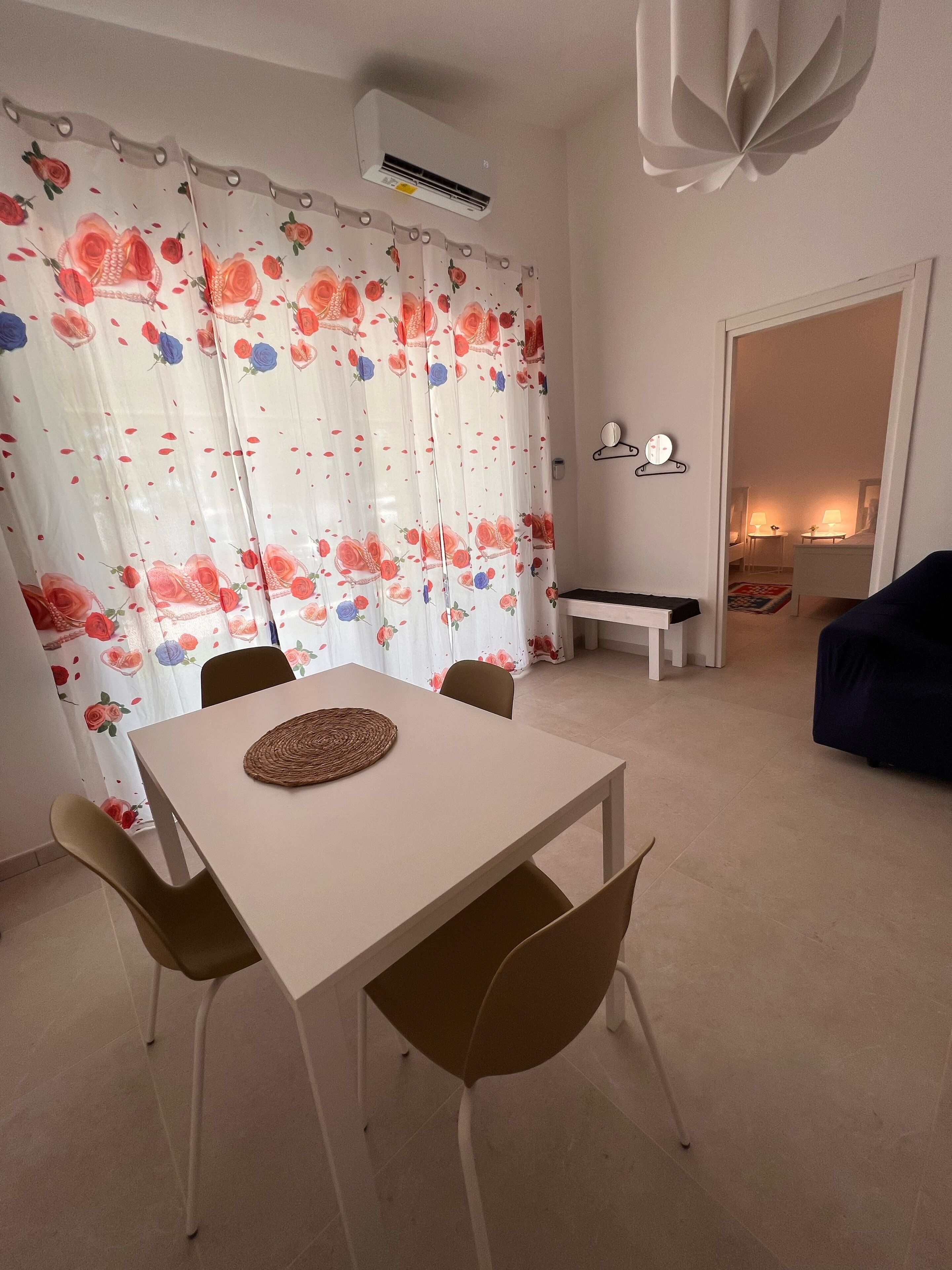A dining area with a table and chairs, a ceiling fan, and a window with floral curtains.