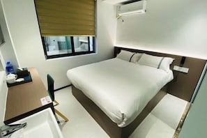 A hotel room with a bed, a desk with a chair, a window with blinds, and an air conditioning unit. - Fuzhou Xiao Boutique Hotel (Sanfang Qixiang Provincial Hospital) (Fuzhou)