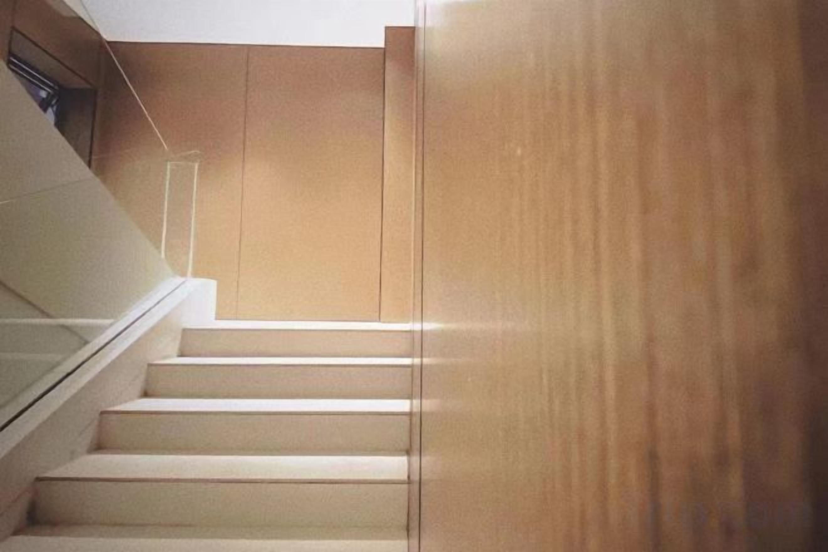 Una scala con finitura in legno e ringhiera in vetro.