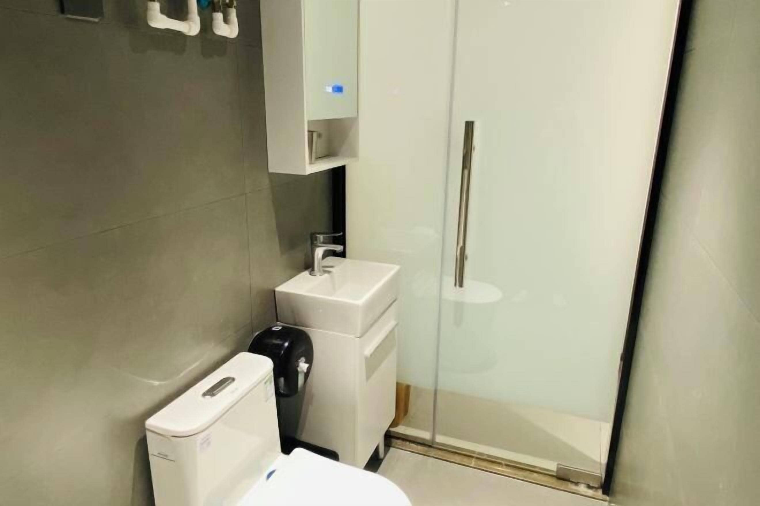 A modern bathroom with a toilet, sink, and glass shower enclosure.