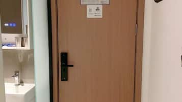 Una puerta de madera con un pomo negro, una pequeña placa con iconos y un gancho fijado a la pared.