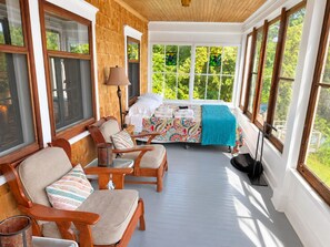 Un solárium con cama, zona de estar y ventanas amplias.