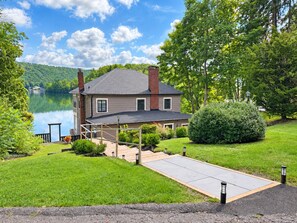 A house with a dock, a grassy yard, and a lake in the background. - Private Lakefront Compound for 16 | Cooperstown Dreams Park Week (Oneonta)