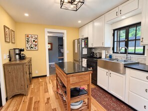 A modern kitchen with white cabinets, a black countertop, and a wooden dining table.