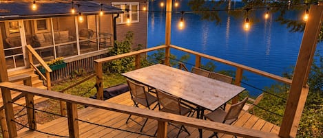 Une terrasse en bois avec une table et des chaises, donnant sur un lac.