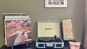 A music-themed display with records, a vintage suitcase, and framed pictures on a cabinet.