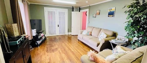 A living room with a sofa, a television, a cabinet, and a plant.