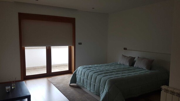 Een slaapkamer met een bed, een tafel en een schuifdeur die leidt naar een balkon.