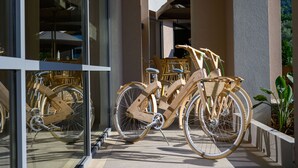Un edificio con facciata in vetro, biciclette di legno parcheggiate all'esterno e un'area patio con sedie e tavoli.