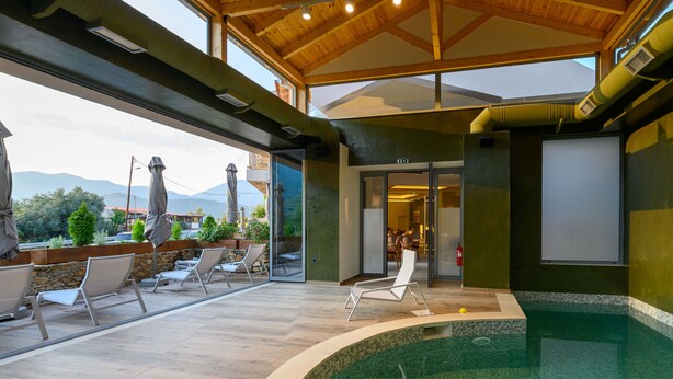 Piscina interna con sedie a sdraio e vista sulle montagne.