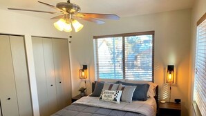 A bedroom with a bed, a ceiling fan, a window with blinds, and bedside lamps. - NEW Condo in Core Area! (Pagosa Springs)