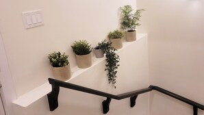 A staircase with a black handrail, white walls, and potted plants on the wall. - Lovely 2 Bedroom Guest Suite in Southwest Edmonton (Edmonton)