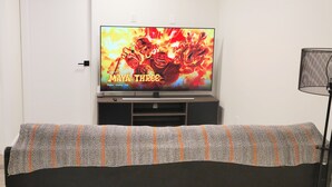 A television displaying 'Maya the Three' on Netflix, a sofa with a patterned cover, and a lamp to the right. - Lovely 2 Bedroom Guest Suite in Southwest Edmonton (Edmonton)