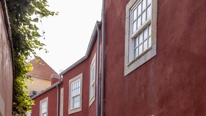 A cobblestone street with red buildings and white window frames. - Studio with courtyard, at 3 min walking from the beach and 20 from center by BUS (Porto)