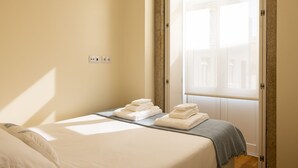 A hotel room with a bed, a window, and a view of buildings outside. - Studio with courtyard, at 3 min walking from the beach and 20 from center by BUS (Porto)