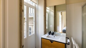 A modern bathroom with a white sink, wooden vanity, and a large mirror. - Studio with courtyard, at 3 min walking from the beach and 20 from center by BUS (Porto)
