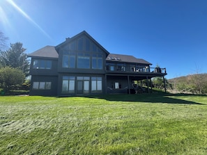 A two-story house with large windows, a covered patio, and a grassy yard.