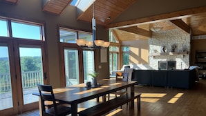 Un vaste espace de vie comprenant une table à manger en bois, des bancs et une cheminée en pierre.