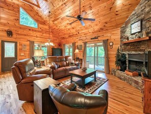 A cabin interior with a wooden ceiling, leather furniture, a fireplace, and a stone accent wall. - Log Cabin in a Gated Community! WIFI. Fire Pit w/ wood provided! Pet-friendly (Waynesville)