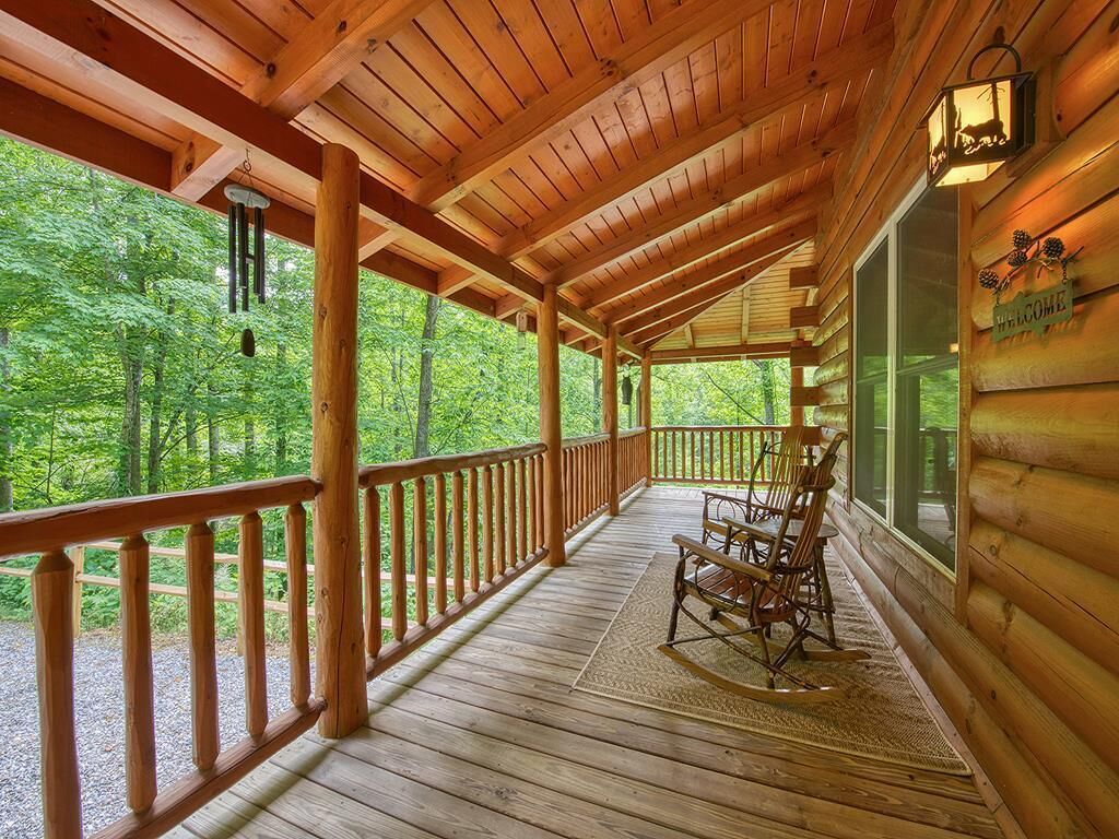 A wooden cabin with a porch, rocking chairs, and a welcome sign.