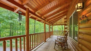Eine Holzjagdhaus mit Veranda, Schaukelstühlen und einem Willkommensschild.