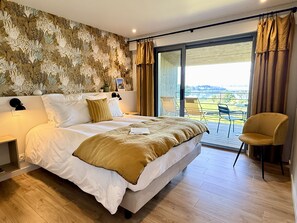 A bedroom with a large bed, a nightstand, a chair, and a view of the outdoors through a sliding door. - La Bellevue Bistrot et Chambres D'hotes (Sene)
