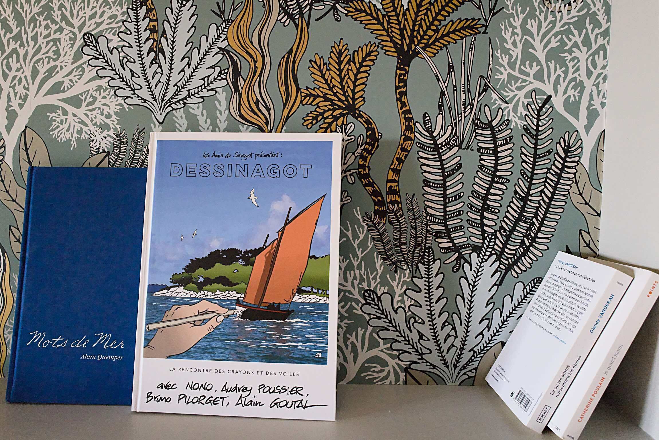 Un livre intitulé « Mots de Mer » d’Alain Quimper, une affiche illustrant un voilier, et un livre intitulé « DESSINAGOT » de Guy Lannaz.