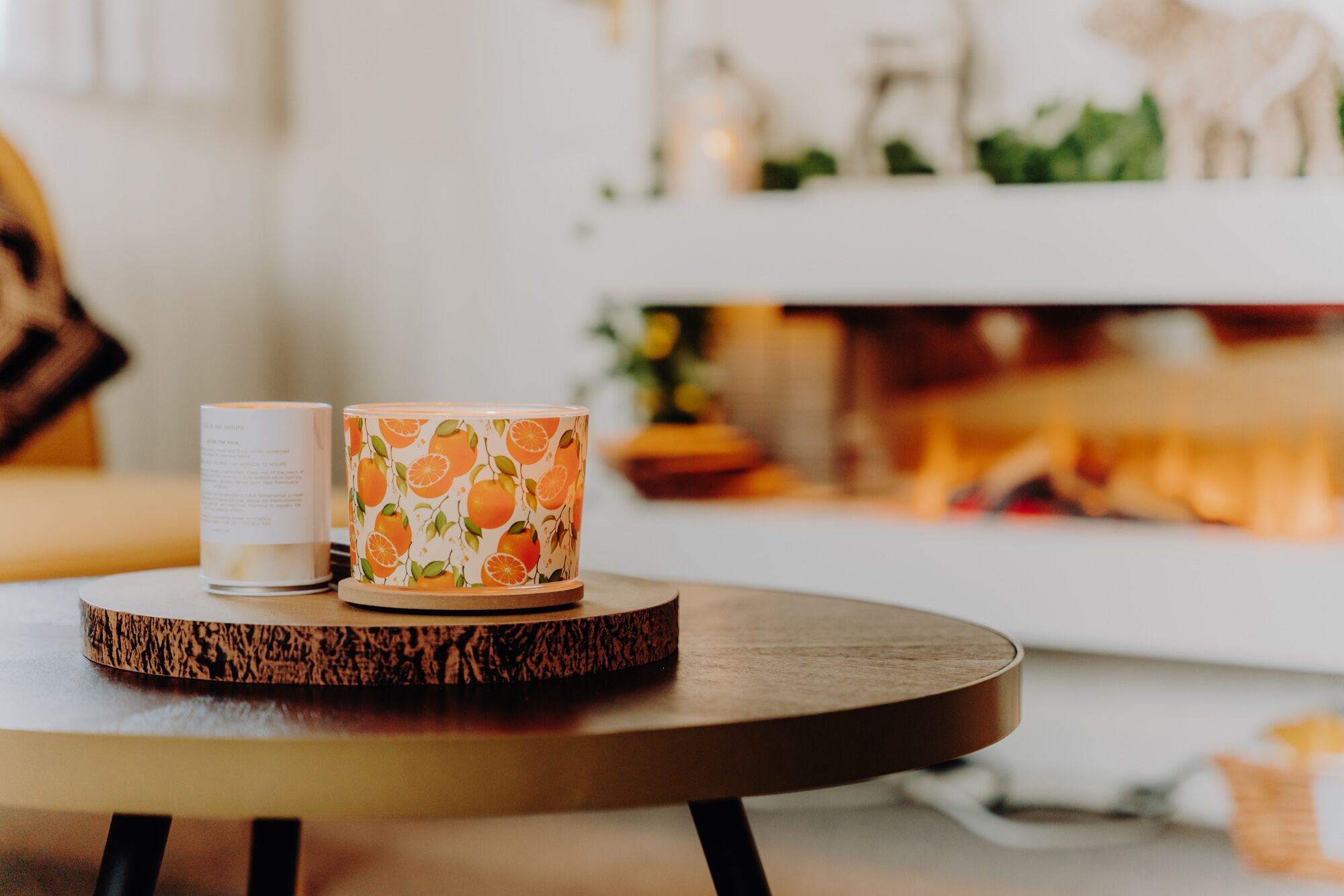 Two cups on a wooden coaster, a white cup with text, and a patterned cup with orange designs.