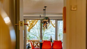 A modern dining area with a wooden floor, red chairs, and a table. - Luxurious Mountain Retreat Lodge Hunters Quay (Dunoon)