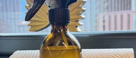A spray bottle labeled "Purdy & Figg" on a table next to a rolled-up towel.