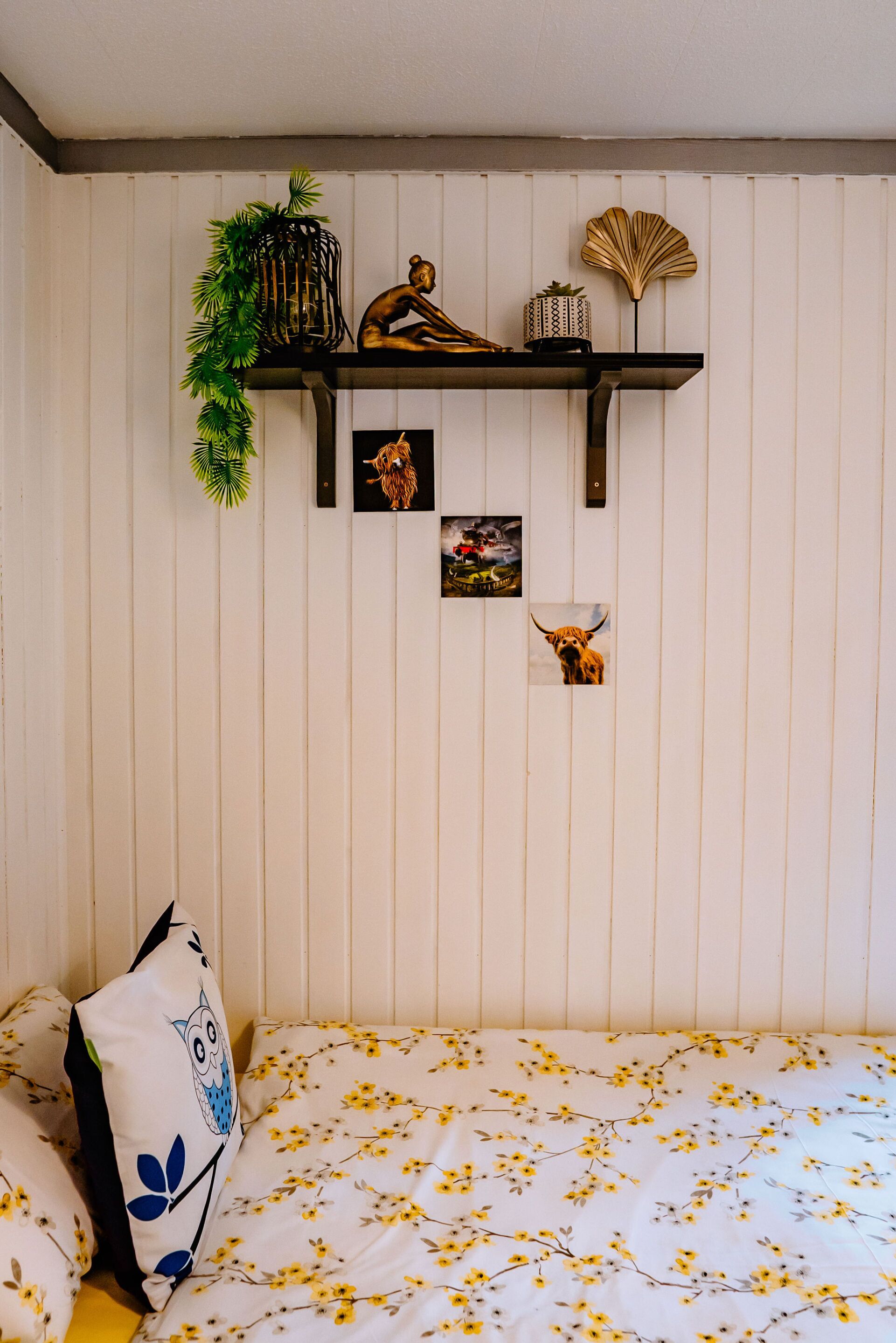Ein Schlafzimmer mit einem Bett, einem Regal mit Dekoration und Bildern an der Wand.