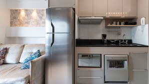 Une cuisine compacte équipée d’un réfrigérateur, d’un four et d’un four à micro-ondes intégrés.