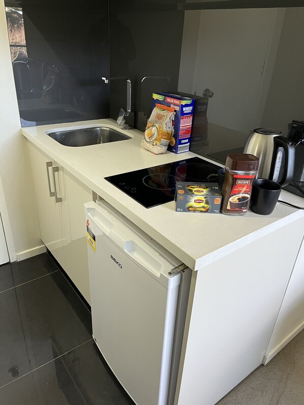 A compact kitchenette with a sink, a built-in stove, and a coffee maker.