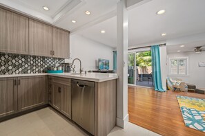 A modern kitchen with wooden cabinets, a stainless steel dishwasher, and a white countertop.