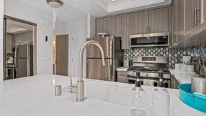 Une cuisine moderne dotée d’appareils électroménagers en acier inoxydable, d’un grand îlot central avec un évier et d’armoires en bois.