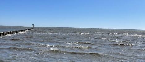 Uma costa rochosa com ondas quebrando na praia e um píer que se estende para a água.