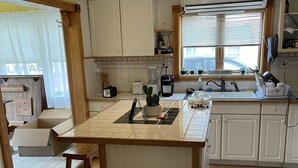 Una cocina con una isla central, armarios de madera, un ventilador de techo y una ventana con persianas.