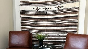 A room with two brown leather chairs, a small black table with a plant, and a striped fabric backdrop.